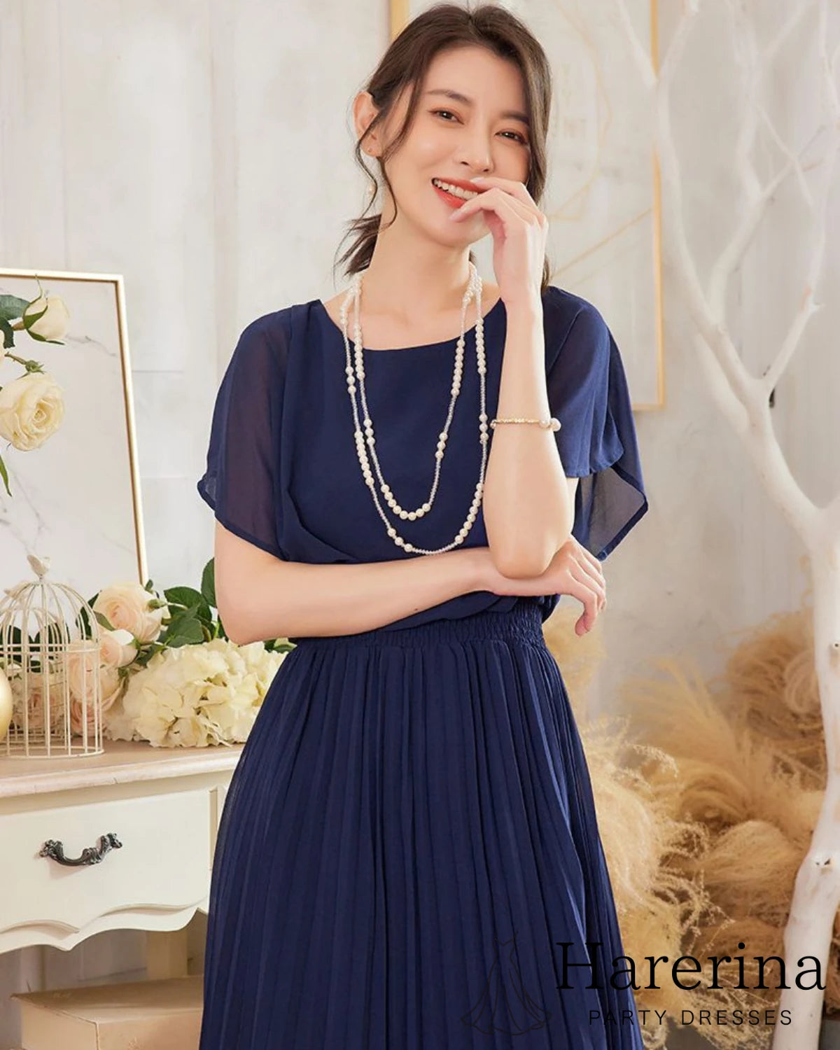 フレアシルエットが美しいシフォンプリーツワンピース（ネイビー）を着た上半身の笑顔ポーズがわかる画像
