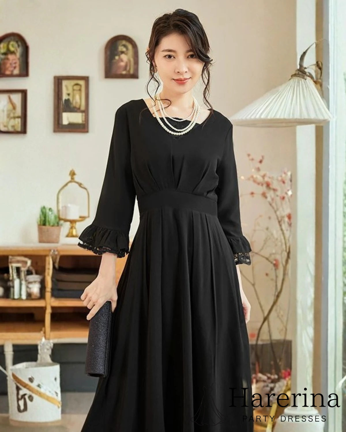 黒のレース袖×フレアシルエットのロングワンピースを着た女性が、上品な表情で正面に立つフォーマルコーディネート写真。
