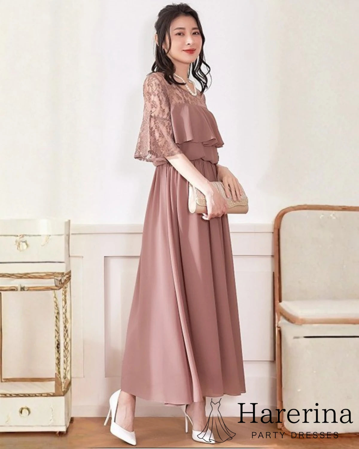 コーラルカラーのフェミニンレーストップ×エアリーシフォンロングワンピースを着た女性が、正面向きで上品に立っている画像
