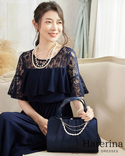 ネイビーのレーストップドレスを着た女性がソファに座って優しく微笑むアップショット
