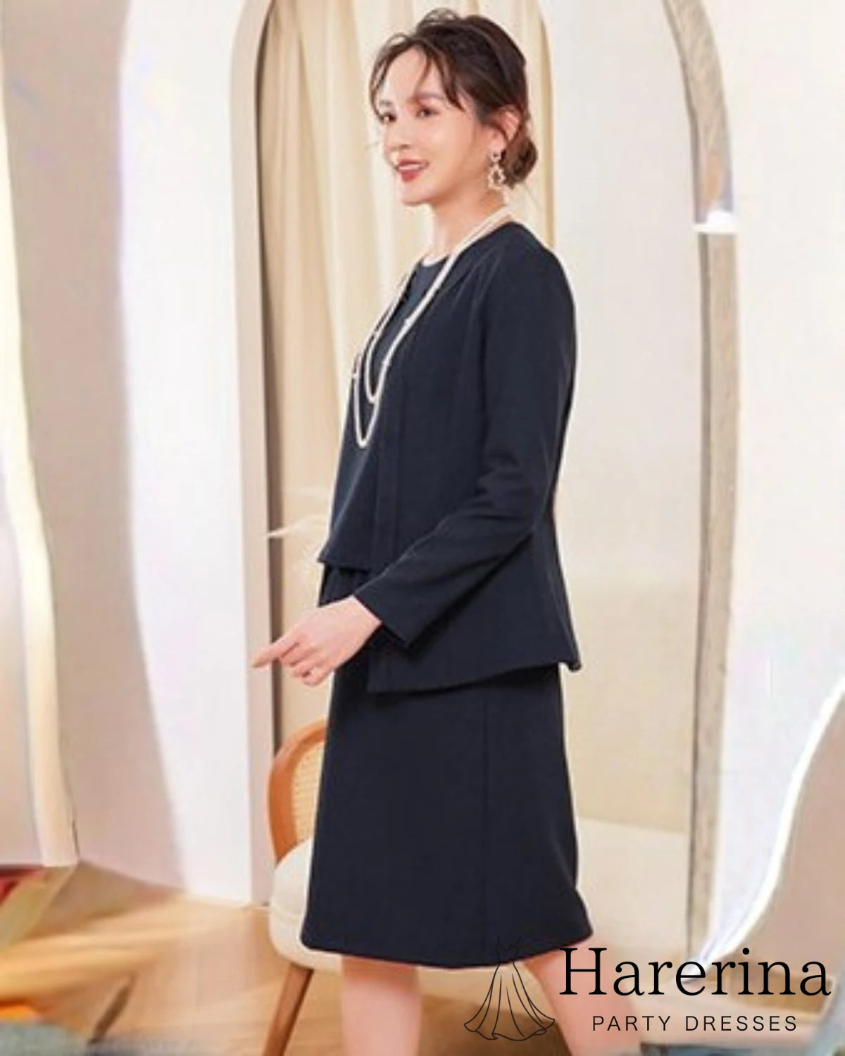 ネイビーのペプラムトップス付き3点セットスーツを着た女性の横向き全身フォーマルコーデ画像
