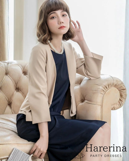 ベージュのペプラム風フォーマルジャケットを着用した女性がソファに座っている上品なショット
