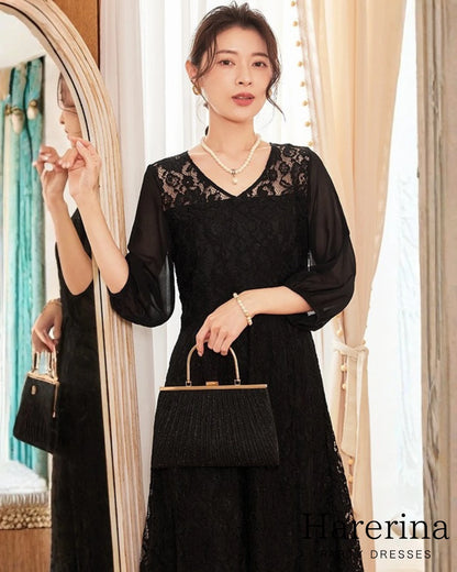 上品レース×シフォン袖ロングワンピースのブラックを着用した女性が、レースのVネックデザインとシフォン袖を見せながら上品に立っている商品イメージ写真。
