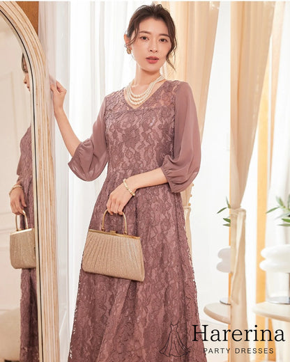 上品レース×シフォン袖ロングワンピースのコーラルピンクを着用した女性が正面で立つ姿。レースの華やかさとシフォン袖の柔らかい質感が引き立つ商品イメージ写真。
