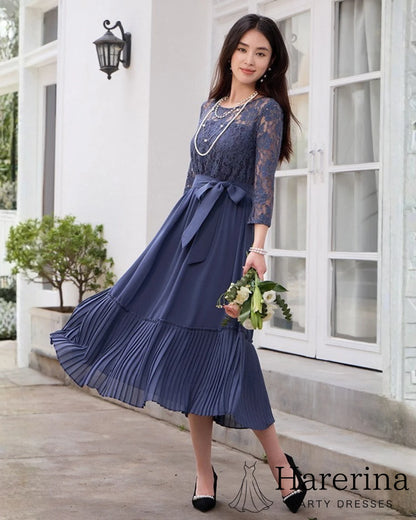 ダークブルーのレースシフォンドレスを着た女性が花束を持って歩くシーンの全身カット
