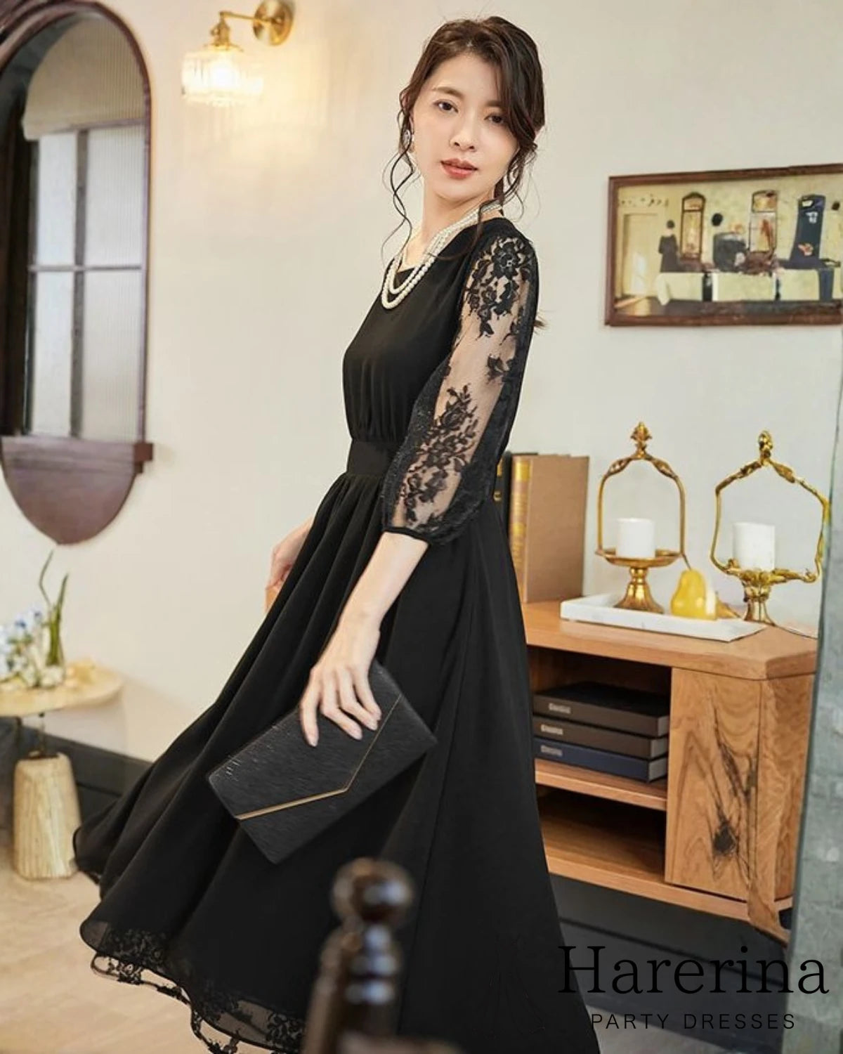 ブラックのレース袖プリーツワンピースを着た女性がクラッチバッグを持って歩いている様子
