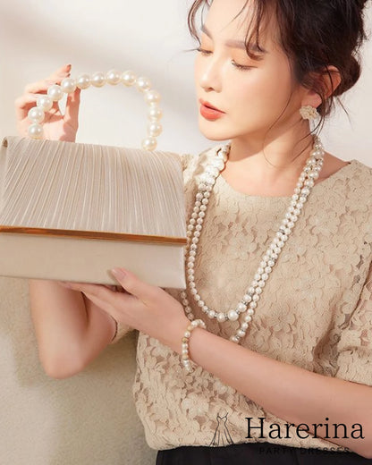 ベージュの華やかプリーツとパール持ち手が魅力のフォーマルクラッチバッグをモデルが持った状態をアップで撮影した画像。プリーツの質感と上品さが確認できる。
