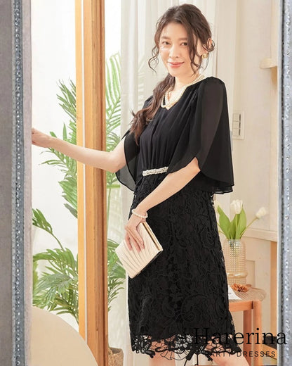 ブラックカラーのパールウエストマーク×膝丈レースドレスを着用した女性を正面から写した画像。シフォン袖とレーススカートが上品で、クラッチバッグを持ったエレガントなスタイル

