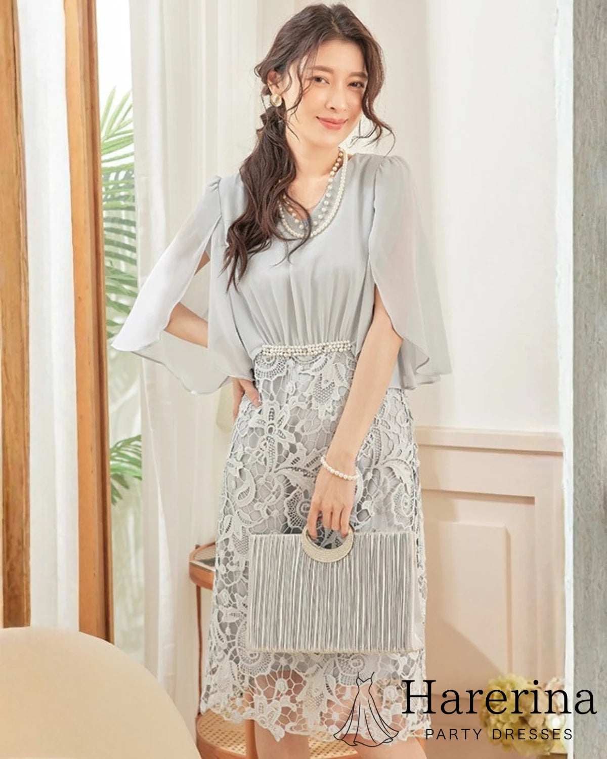 グレーカラーのパールウエストマーク×膝丈レースドレスを着用した女性を正面から写した画像。パールネックレスとフリンジバッグを合わせた上品なコーディネート
