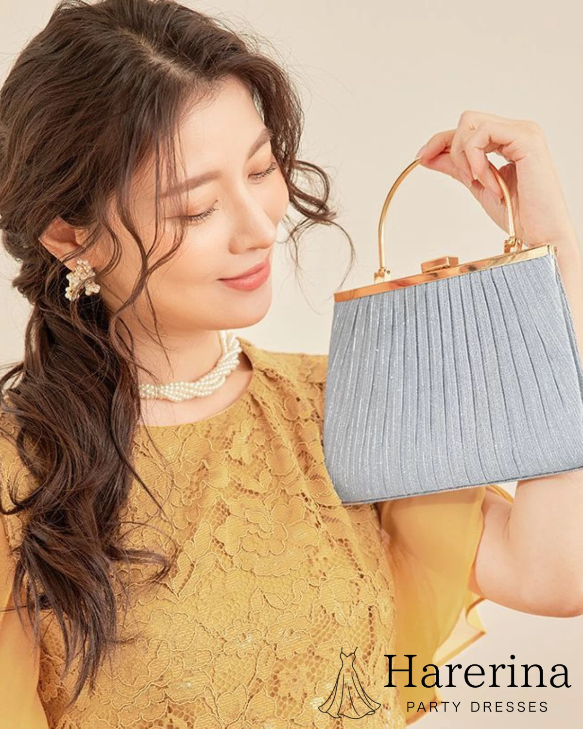 プリーツ×メタルハンドルの華やかパーティーバッグ シルバーをモデルが胸元で持った華やかなアップ写真
