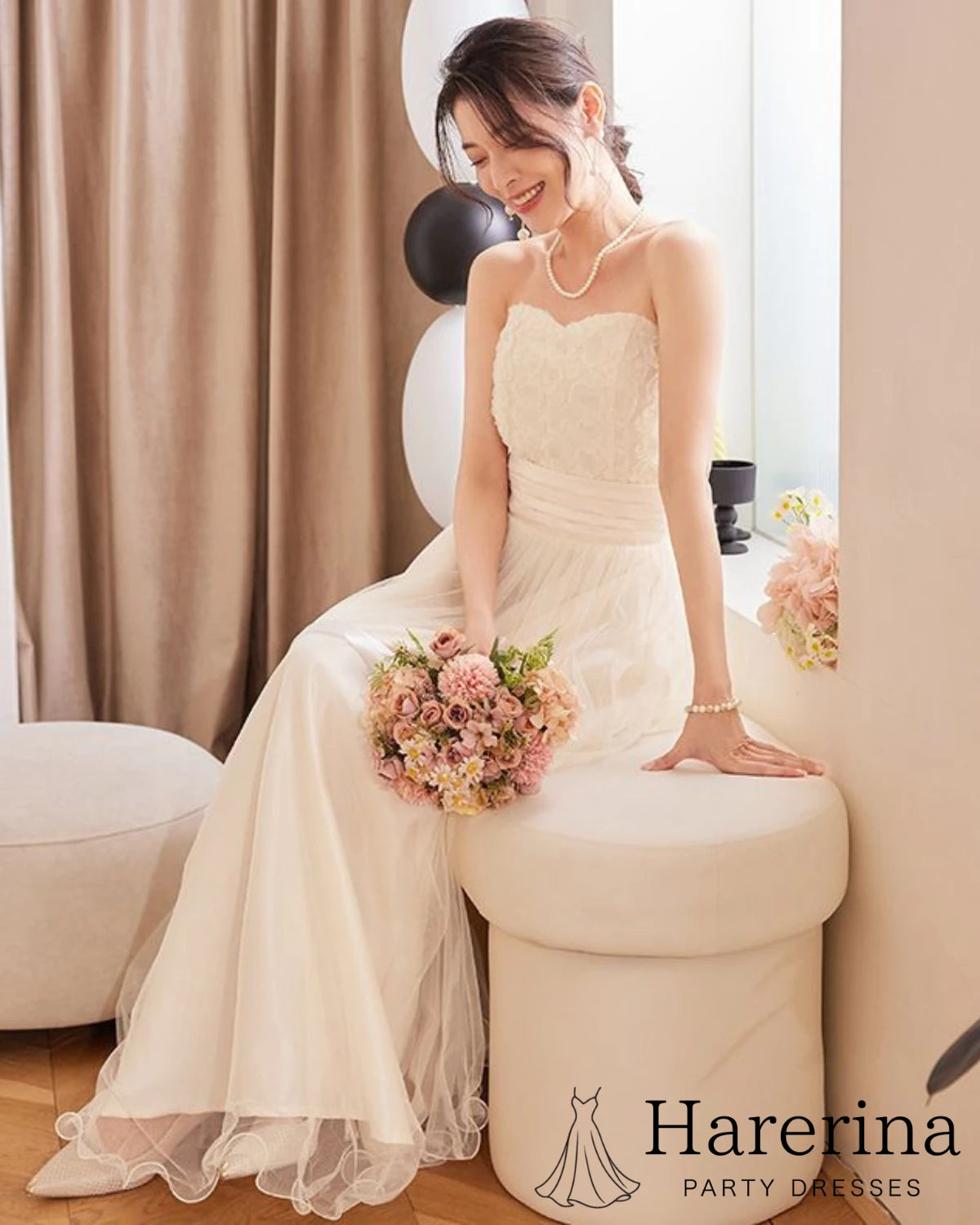 アプリコットのサテン×スパンコール チュールロングドレスを着た女性が座って微笑む様子の画像。
