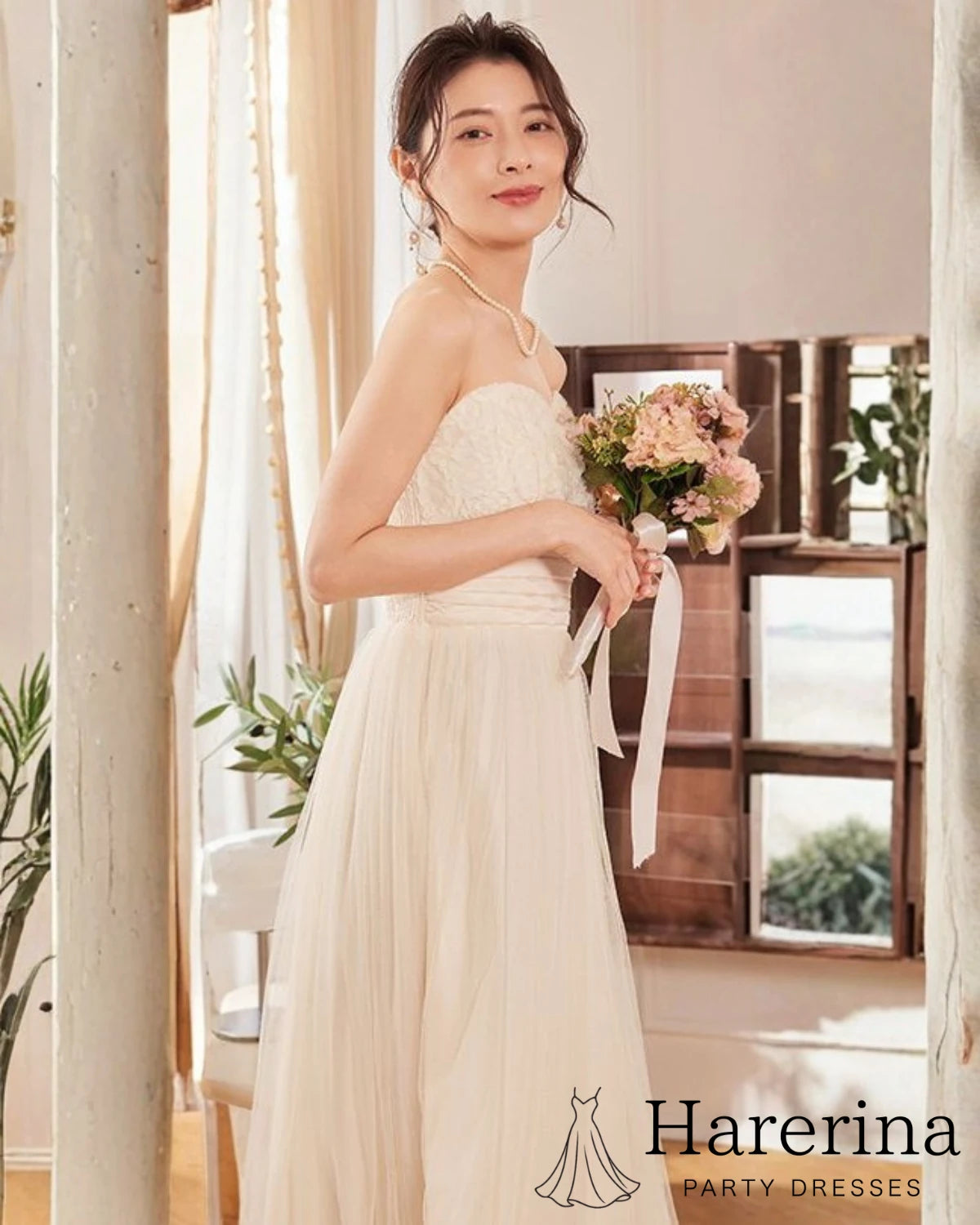 アプリコットのサテン×スパンコール チュールロングドレスを着た女性が横向きでブーケを持つ写真。
